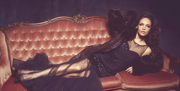 Vacker kvinna i svart klänning på soffa — Stockfoto