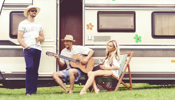 happy friends relaxing near trailer