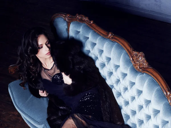 Bela mulher em vestido preto no sofá — Fotografia de Stock