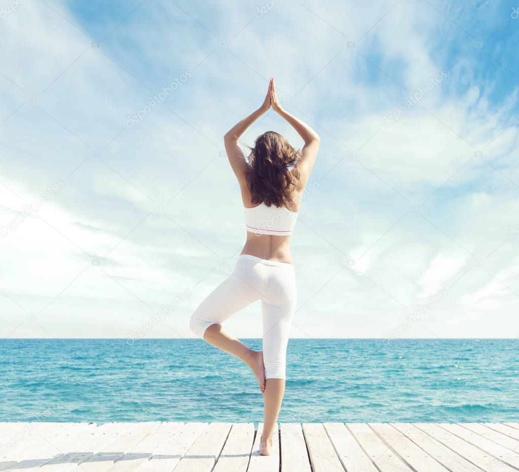 Woman meditating on wooden pier