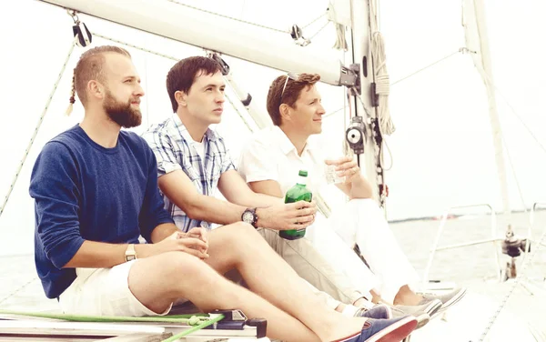 Друзья сидят на яхте и пьют — стоковое фото
