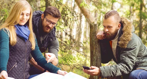 Vänner kontrollera karta i skogen — Stockfoto