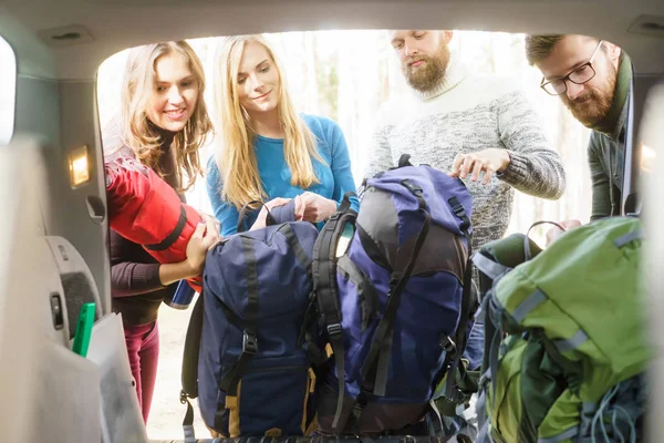 friends taking backpacks out of car