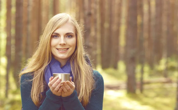 Mulher bebendo chá de garrafa térmica na floresta — Fotografia de Stock