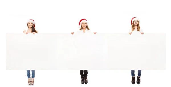 Подростки в рождественских шляпах с чистым рекламным щитом — стоковое фото