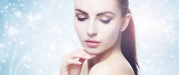 Portrait of young, beautiful and healthy woman: over winter background. Healthcare, spa, makeup and face lifting concept. Stock Picture