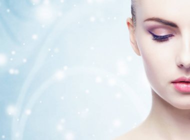genç, güzel, taze ve sağlıklı kadın kar taneleri ile mavi arka plan yüzünden kırpılmış portresi