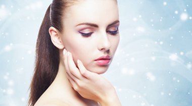 genç, güzel, taze ve sağlıklı kadın kar taneleri ile mavi arka plan yüzünden closeup portresi