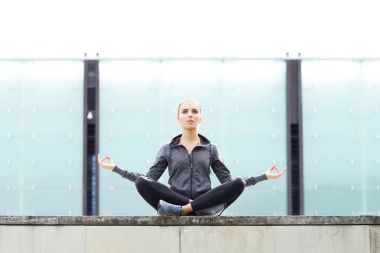 genç, zinde ve sportif kadın kentsel inşaat çatıda oturan yoga meditasyon yapıyor. Fitness, spor ve sağlıklı yaşam konsepti