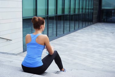 genç, zinde ve sportif kadın merdivenlerde, oturan eğitim sonra dinlenmek arkadan görünüm. Fitness, spor, kentsel koşu ve sağlıklı yaşam konsepti