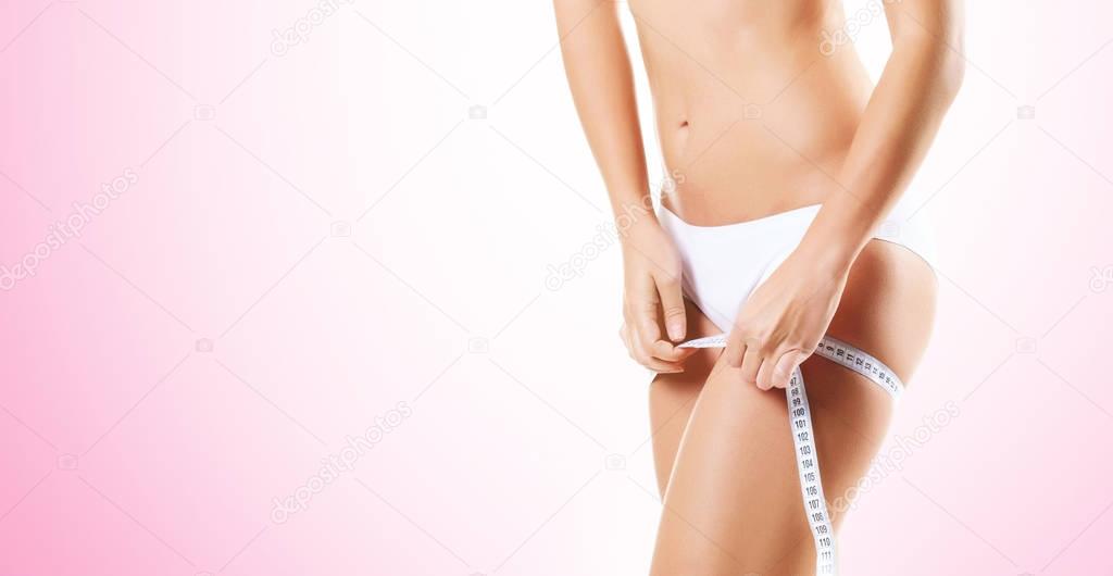 cropped photo of fit and sporty woman in white lingerie measuring body over pink background. Sport, fitness, diet, weight loss and healthcare concept 