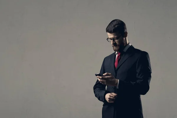 Geschäftsmann mit Smartphone steht über weißer Wand. — Stockfoto