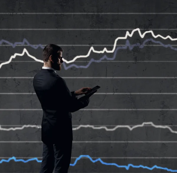 Empresario con teléfono inteligente de pie sobre el fondo del diagrama. Negocios, finanzas, concepto de inversión . —  Fotos de Stock