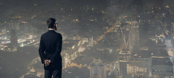 Businessman standing over night city background.