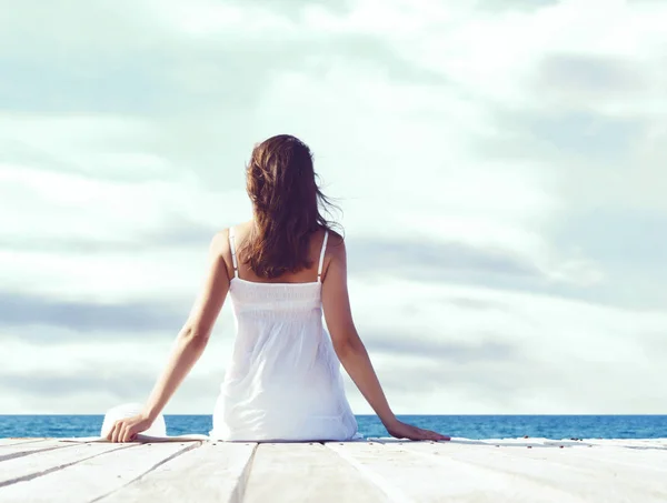美しく 健康的な女の子の木製の桟橋の上に座っての背面からの眺め リゾートおよび概念を旅行 — ストック写真
