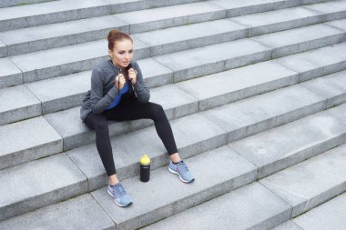 Genç, uygun ve sportif kız eğitimden sonra dinlenme. Fitness, spor, kentsel koşu ve sağlıklı yaşam konsepti.