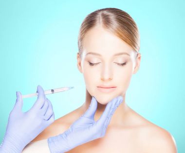 Genç bir kadının güzel yüzüne iğne yapan bir doktor. Estetik ameliyat konsepti.