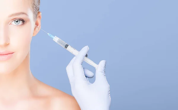 若くて青い背景の上の皮膚の注射を持つ美しい女性 整形外科のコンセプト — ストック写真