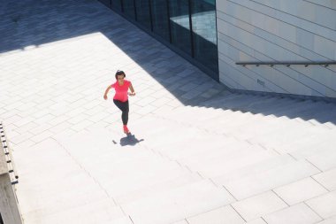 Genç, uygun ve merdivenlerden yukarı koşan sportif kız. Fitness, spor, kentsel koşu ve sağlıklı yaşam konsepti.