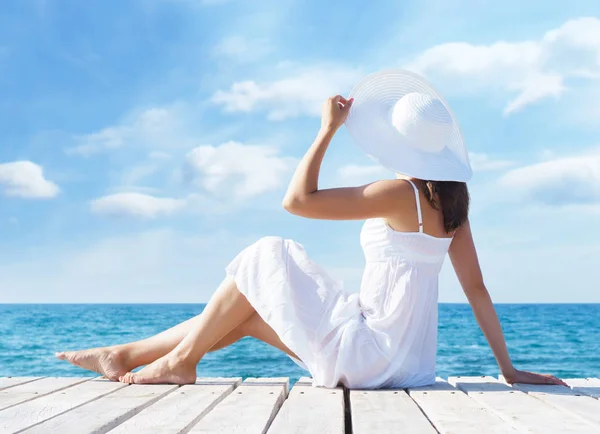 美丽的年轻女子在木墩上夏天的白色礼服 海和晴朗的天空背景 自由的概念 — 图库照片