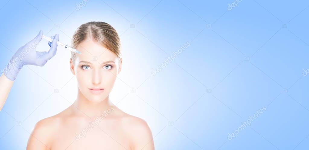 Young, beautiful and healthy woman having skin injections over blue background. Plastic surgery concept.