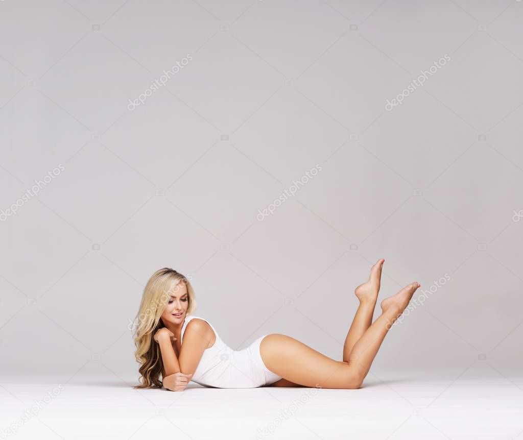 Young, beautiful and sporty woman in slimming underwear. Woman in white lingerie over grey background.