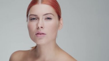 Cilt bakımı kremi süren genç, güzel ve doğal kızıl saçlı kadının stüdyo portresi. Yüz gerdirme, kozmetik ve makyaj konsepti.