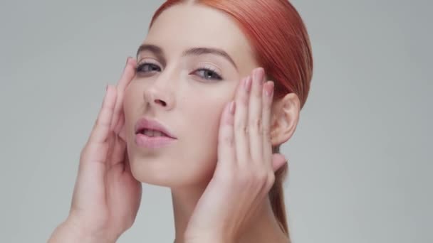 若いのスタジオの肖像画 スキンケアクリームを適用する美しく 自然な赤毛の女性 顔の持ち上げ 化粧品 化粧品のコンセプト — ストック動画