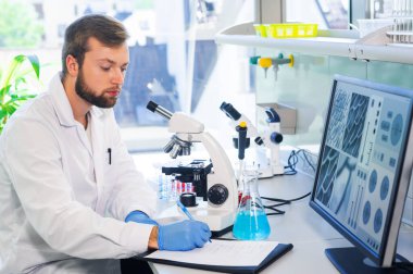 Laboratuvarda çalışan bir bilim adamı. Doktor mikrobiyoloji araştırması yapıyor. Laboratuvar aletleri: mikroskop, test tüpleri, ekipmanlar. Biyoteknoloji, kimya, bakteriyoloji, viroloji, DNA ve sağlık hizmetleri kavramı.