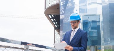 Kasklı emlak müteahhidi. Yeni ofis inşaatı. Modern ofis binası önünde kendine güvenen iş adamları veya mimar.
