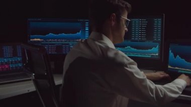 İşyeri ve analiz teknolojisi kullanarak geceleri ofiste çalışan bir tüccar. Borsa, kripto para birimi, küresel iş, finansal ticaret ve bankacılık kavramı.