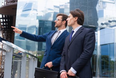 Kendine güvenen iş adamları modern ofis binasının önünde konuşuyorlar. İş adamı ve iş arkadaşı. Bankacılık ve finans piyasası kavramı.