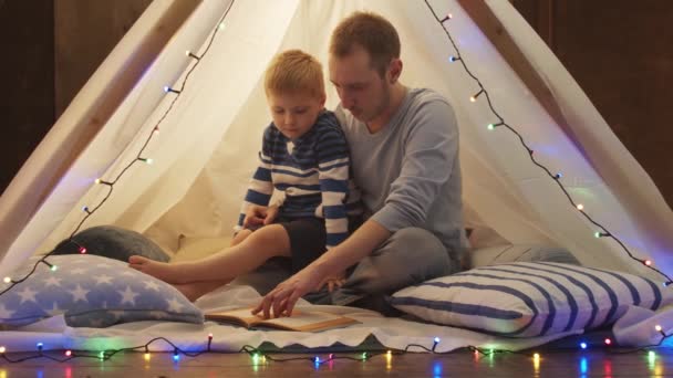 晚上小男孩在家里孩子们的帐篷里玩耍 父亲读童话 在游戏室里快乐的高加索小孩 — 图库视频影像