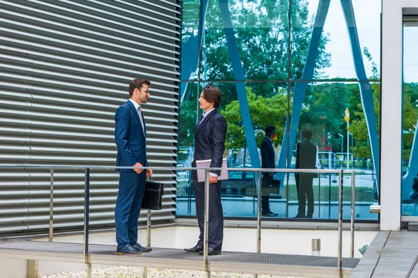近代的なオフィスビルの前で話す自信のあるビジネスマン ビジネスマンと彼の同僚銀行と金融市場の概念 — ストック写真