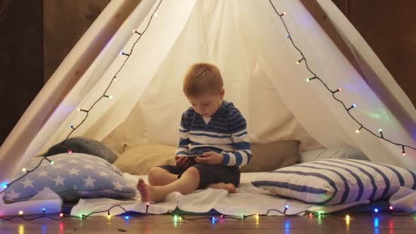 Маленький Мальчик Играет Смартфоном Детской Палатке Дома Вечером Счастливого Белого — стоковое видео