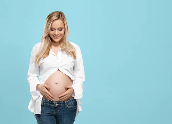 Jonge Zwangere Vrouw Studio Omarmt Haar Mooie Buik Cyaan Achtergrond — Stockfoto