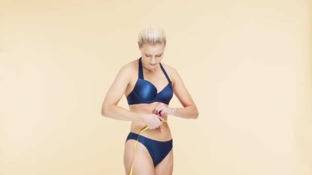 彼女の完璧な体を測定青い水着で若い 美しく フィット感と自然なブロンドの女性 スポーツ フィットネス スキンケア セルライト除去 食事と減量の概念 — ストック動画