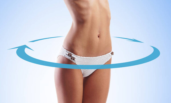 Close-up of thin and beautiful female body. Blue background. Weight loss, sports, exercising, water balance, healthy nutrition concept. Blue arrows.