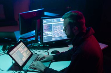 Aranan hackerlar virüs fidye yazılımını bodrumdaki bilgisayar ve dizüstü bilgisayarlarla kodluyorlar. Siber saldırı, sistem kırma ve kötü amaçlı yazılım kavramı.