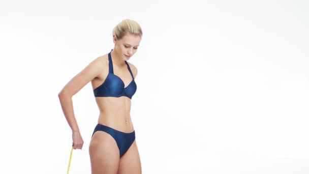 自然的金发女人穿着蓝色泳衣 在孤立的白色背景上测量她完美的身体 清除脂肪 节食和减肥概念 — 图库视频影像