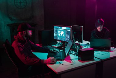 Aranan hackerlar virüs fidye yazılımını bodrumdaki bilgisayar ve dizüstü bilgisayarlarla kodluyorlar. Siber saldırı, sistem kırma ve kötü amaçlı yazılım kavramı.