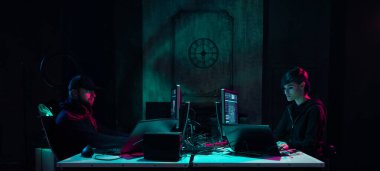 Aranan hackerlar virüs fidye yazılımını bodrumdaki bilgisayar ve dizüstü bilgisayarlarla kodluyorlar. Siber saldırı, sistem kırma ve kötü amaçlı yazılım kavramı.