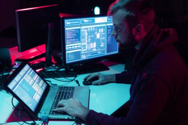 Aranan hackerlar virüs fidye yazılımını bodrumdaki bilgisayar ve dizüstü bilgisayarlarla kodluyorlar. Siber saldırı, sistem kırma ve kötü amaçlı yazılım kavramı.
