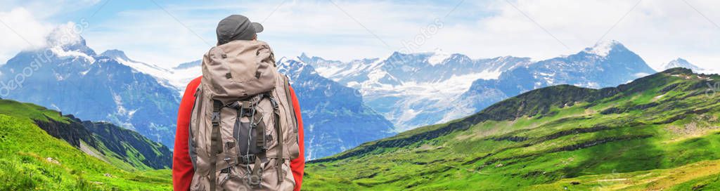 Traveler with backpack. Alpine peaks of Grindelwald and Jungfrau. Landscape background of Bernese highland. Alps, tourism, journey, traveling and hiking concept.
