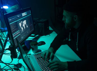 Aranan hackerlar virüs fidye yazılımını bodrumdaki bilgisayar ve dizüstü bilgisayarlarla kodluyorlar. Siber saldırı, sistem kırma ve kötü amaçlı yazılım kavramı.