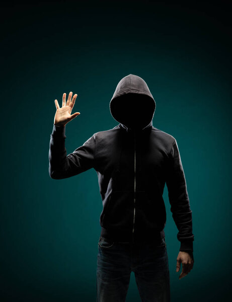 Portrait of computer hacker in hoodie. Obscured dark face. Data thief, internet fraud, darknet and cyber security concept.