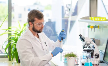 Laboratuvarda çalışan bir bilim adamı. Doktor mikrobiyoloji araştırması yapıyor. Laboratuvar aletleri: mikroskop, test tüpleri, ekipmanlar. Biyoteknoloji, genetik, biyokimya, ilaç, DNA ve sağlık hizmetleri kavramı.