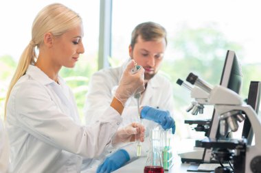 Laboratuvarda çalışan bir bilim adamı. Doktorlar tıbbi araştırma yapıyor. Laboratuvar aletleri: mikroskop, test tüpleri, ekipmanlar. Biyoteknoloji, kimya, bilim, deneyler ve sağlık konsepti. Gün ışığı ve