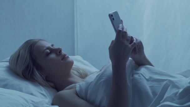 Ung Kvinna Som Ligger Sängen Med Smartphone Natten Vacker Blond — Stockvideo