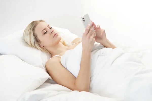 Mujer Joven Acostada Cama Con Smartphone Hermosa Chica Rubia Despierta — Foto de Stock